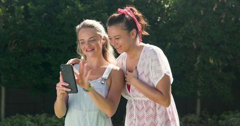 Female Friends Checking Smartphone and Fitness Tracker Outdoors