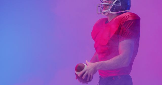 Football player dressed in red jersey and helmet holding a football with colorful smoke in the background. Useful for marketing materials for sports events, football-themed ads, team promotions, athlete spotlights, or energetic visuals emphasizing performance and competition.