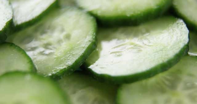 Close-up view of fresh cucumber slices arranged on a surface, with copy space. Cucumber slices are commonly used in culinary contexts and for skincare routines due to their hydrating properties.