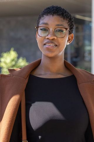Confident african american professional woman wearing glasses and coat, urban portrait