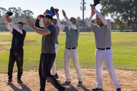 Teammates raising caps celebrating victory and unity on baseball diamond