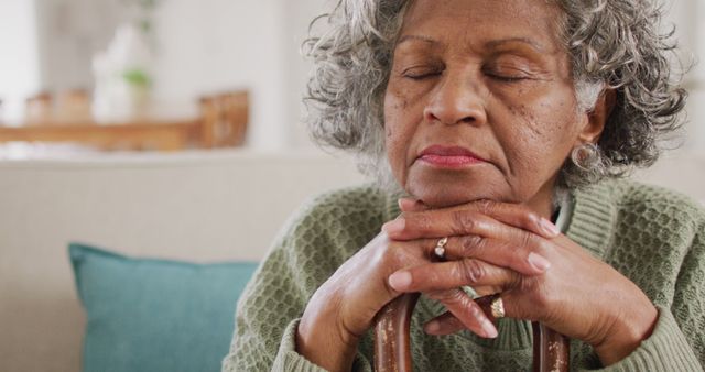 Portrait of tired senior african american woman sitting on sofa, leaning on walking cane - Download Free Stock Photos Pikwizard.com