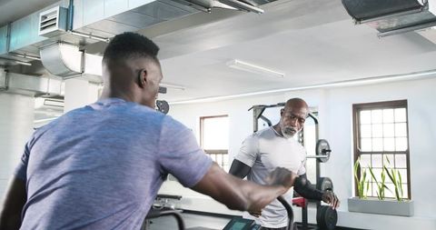 Trainer Guiding Senior Man on Gym Treadmill