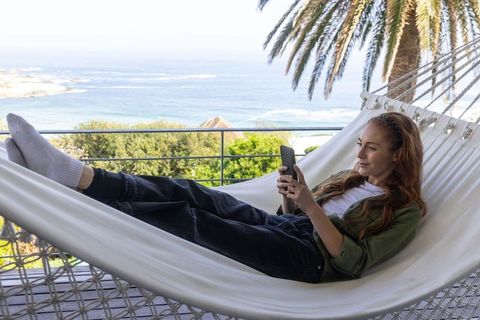 Woman Relaxing on Seaside Hammock with Smartphone