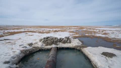 Desolate Tundra with Melting Ice and Abandoned Pipe