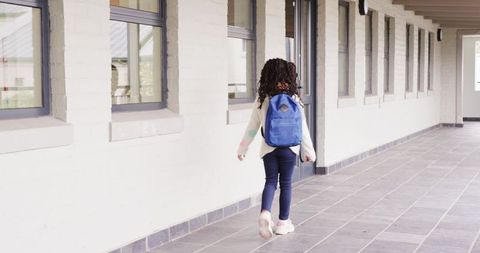 Young Student Walking Down School Corridor with Backpack