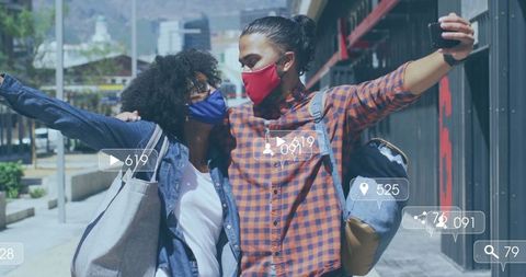 Masking couple capturing joyful selfie in urban setting