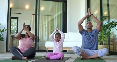 Diverse family practicing yoga together at home morning mindfulness and meditation