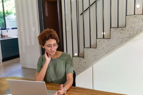 African american woman video conferencing on laptop in modern sunlit home