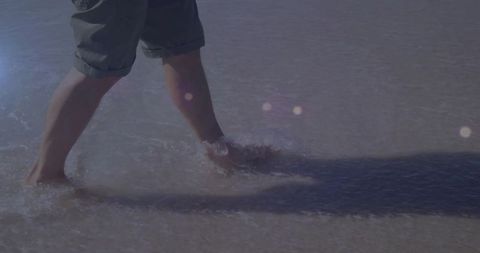 Man wading through shallow water on beach