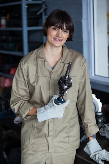 Female mechanic holding an car parts at a repair garage