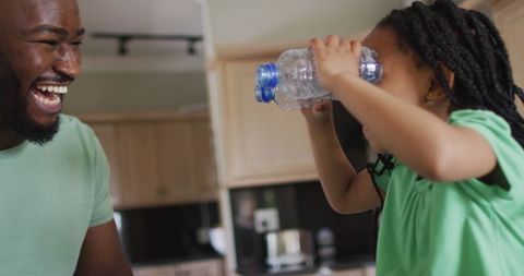 Father and Daughter Playing with Recyclable Bottles in Kitchen