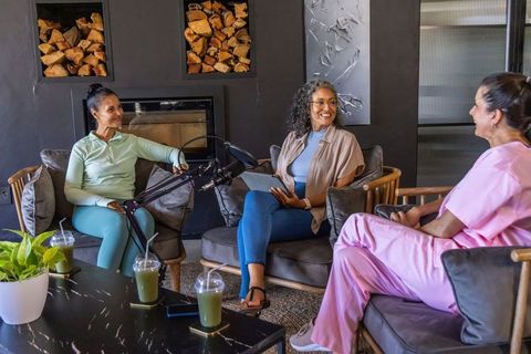 Multicultural women recording wellness podcast in cozy lounge with tablet and smoothies
