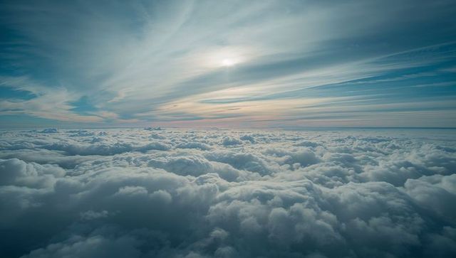 Ethereal high-altitude cloudscape with pastel sunrise horizon and endless cumulus sea