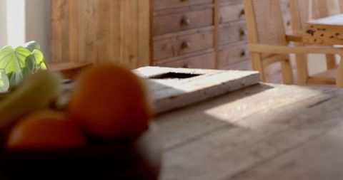 Sunlit rustic dining table with fresh fruit bowl