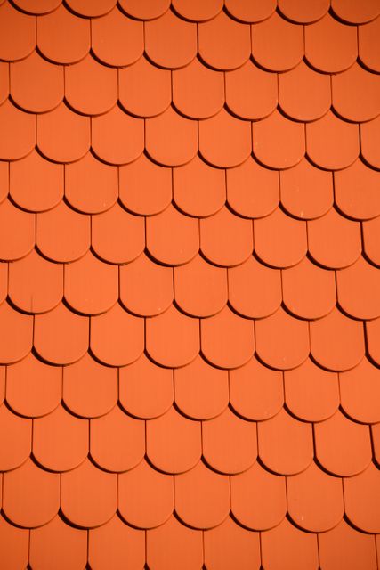 This image shows a close-up of red roof tiles arranged in a symmetrical pattern. It can be used for projects related to construction, architectural designs, materials, and textures.
