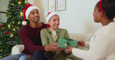 Friends Sharing Holiday Gifts by Christmas Tree