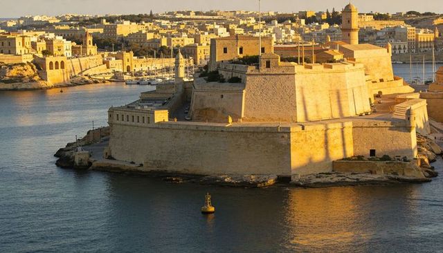 Sunlit limestone fortress basking over historic mediterranean harbor at golden hour