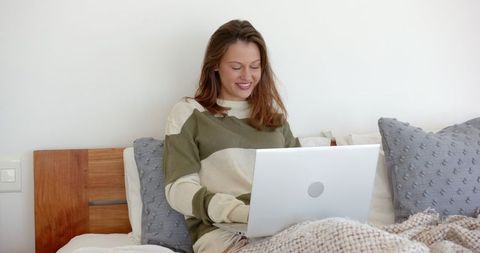 Woman Relaxing and Working on Laptop in Cozy Bedroom