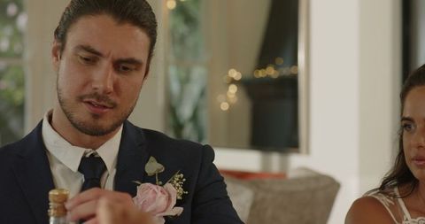Groom opening bottle with bride celebrating wedding day