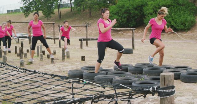 Determined caucasian female friends in pink t shirts crossing logs and tyres at bootcamp training - Download Free Stock Photos Pikwizard.com