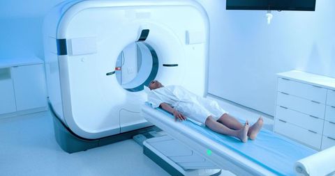 African american man undergoing ct scan on motorized table in modern radiology suite wearing gown