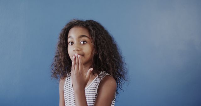 Curious Girl Holding Hand Over Mouth Against Blue Background - Download Free Stock Images Pikwizard.com