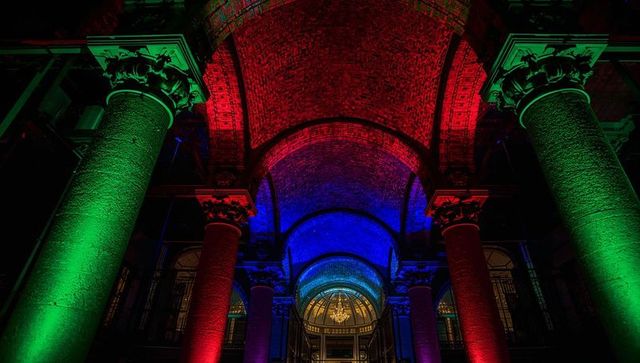 Rgb illuminating historic arched entrance with columns and vaulted ceiling at night