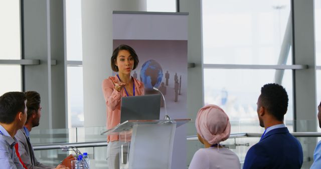 An Asian woman delivers a speech at a business seminar from a podium with her laptop. - Download Free Stock Photos Pikwizard.com