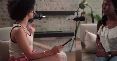 African american women recording cozy at-home podcast interview with tablet