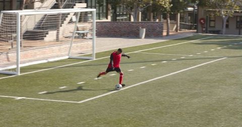 Soccer Player Striking Soccer Ball Near Goal on Green Field