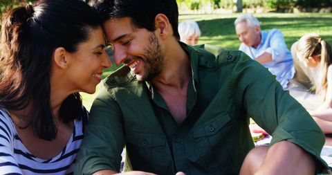 Young Couple Sharing Intimate Moment in Park on Sunny Day