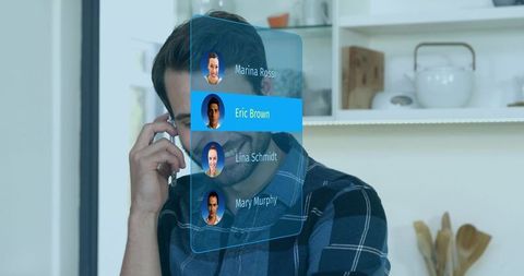 Man holding smartphone talking while using holographic contact list in modern kitchen