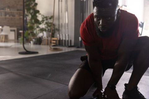 African american athlete checking smartwatch after battle rope workout in industrial gym