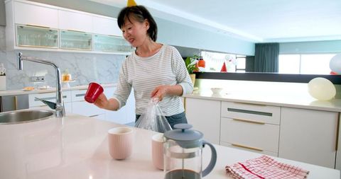 Senior woman tidying up kitchen after birthday celebration