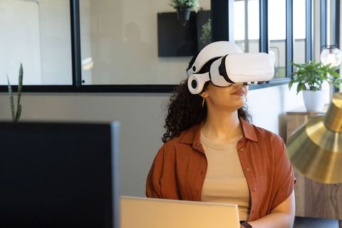 African american professional using vr headset at modern office desk with laptop