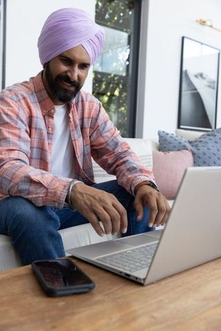 Indian Man Working from Home Living Room on Laptop