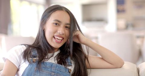 Smiling Teenage Girl Relaxing at Home in Denim Overalls