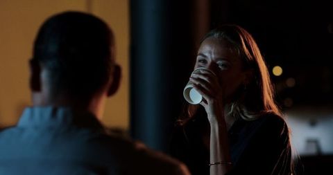 Engaged woman holding coffee during nighttime business meeting
