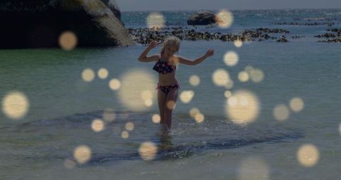 Child wading in rocky cove wearing star print swimsuit