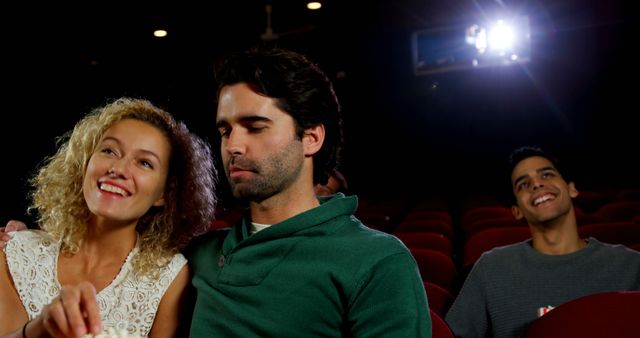 Group of friends sitting in a dark movie theater watching a film. Perfect for illustrating concepts of social activities, friendship, relaxation, entertainment, and leisure time in a cinema setting. Useful for marketing campaigns related to movies, theaters, social events, or lifestyle blogs.