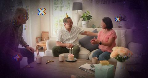 Couple celebrating birthday on cozy living room sofa with cake, candles, gifts and roses