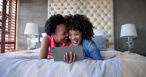 Diverse Female Couple Relaxing on Bed, Sharing Happy Moments