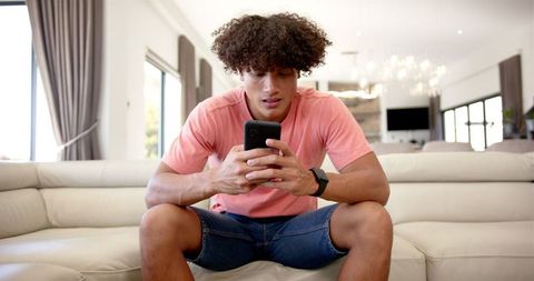 Upset young man interacting with smartphone in modern living room