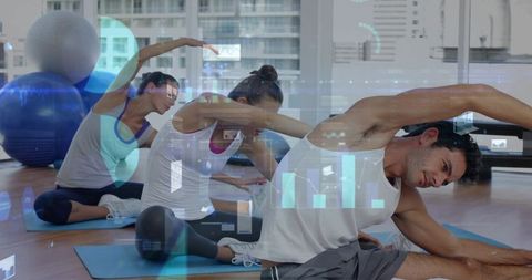 Group fitness class performing side bends on mats in sunlit studio with stability balls