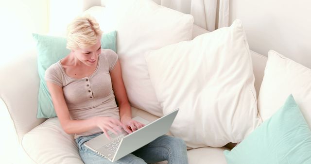 Smiling Woman Working on Laptop While Sitting on Comfortable Couch at Home - Download Free Stock Images Pikwizard.com