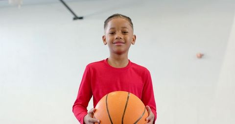 Preteen boy holding basketball in gymnasium