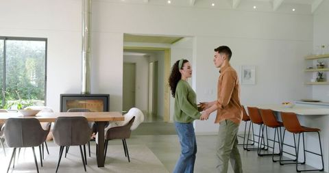Couple Holding Hands in Open High-End Modern Kitchen-Dining Area