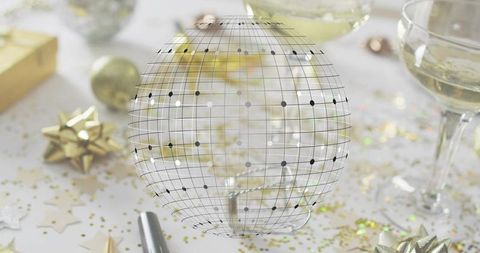 Translucent Wireframe Globe Hovering Over Festive Champagne Table with Gold Confetti