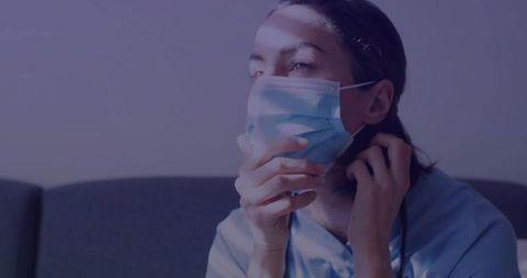 Healthcare Worker Relaxing in Lounge Adjusting Surgical Mask